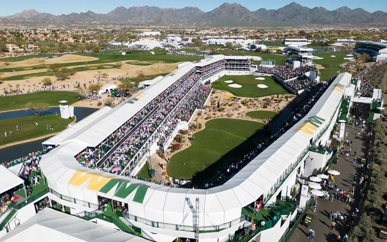 An aerial view of a packed desert golf hole, with mountains behind the grandstand.